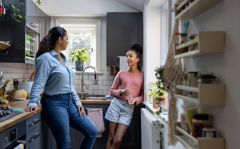 mother and teen daughter chatting in the kitchen